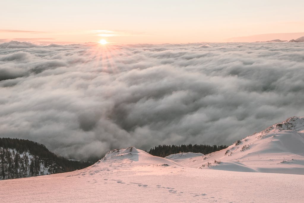 Breathtaking view of sunrise over a snow-covered mountain and a sea of clouds, capturing nature's serene beauty.